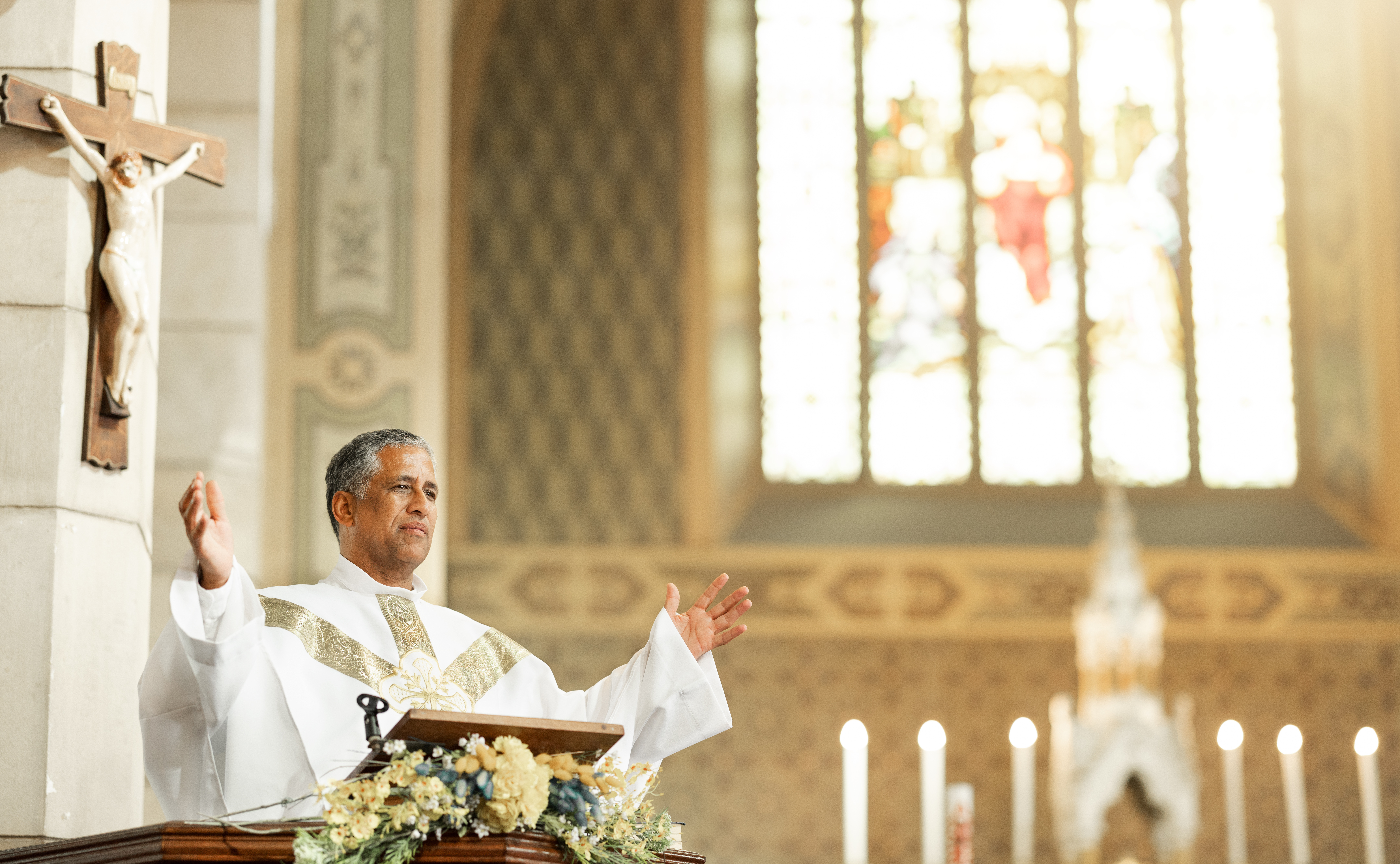 Religion, Christianity and priest speaking in church with arms raised standing by podium. Ceremony,.
